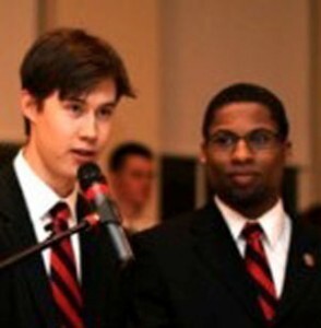 J.D. Merrill '13 speaks at the podium with Jordan Starck '12 standing next to him