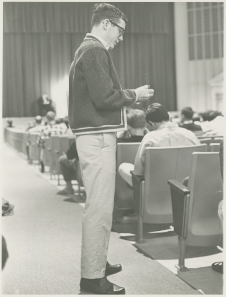 A student recording the names of absent students during chapel, 1967.