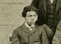 Tom, a young black man dressed formally in a jacket and tie