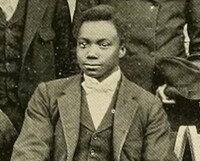 Otho, a young black man dressed formally in a jacket and tie.