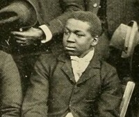 "Jim", a young black man dressed formally in a jacket and tie.