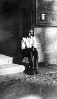 Baxter Williamson, an older black man in a dress shirt sitting in a doorway
